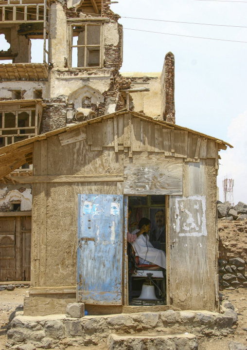 Hairdresser cutting man hair in a small house, Taiz Governorate, Mokha, Yemen
