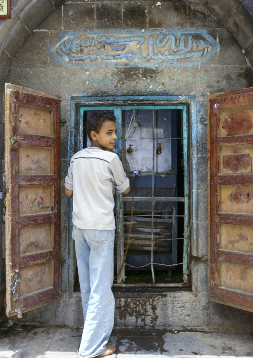 Yemeni boy drinking in a public fountain in the street, Amanat Al-Asemah, Sanaa, Yemen