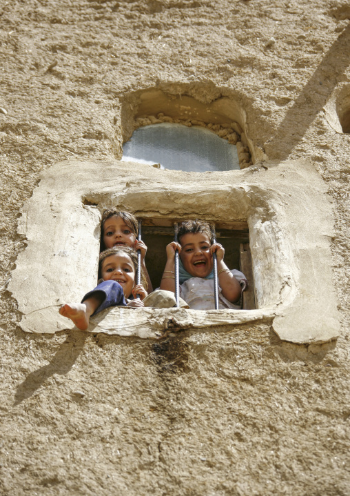 Yemeni girls standing behind a window, Amran Governorate, Amran, Yemen